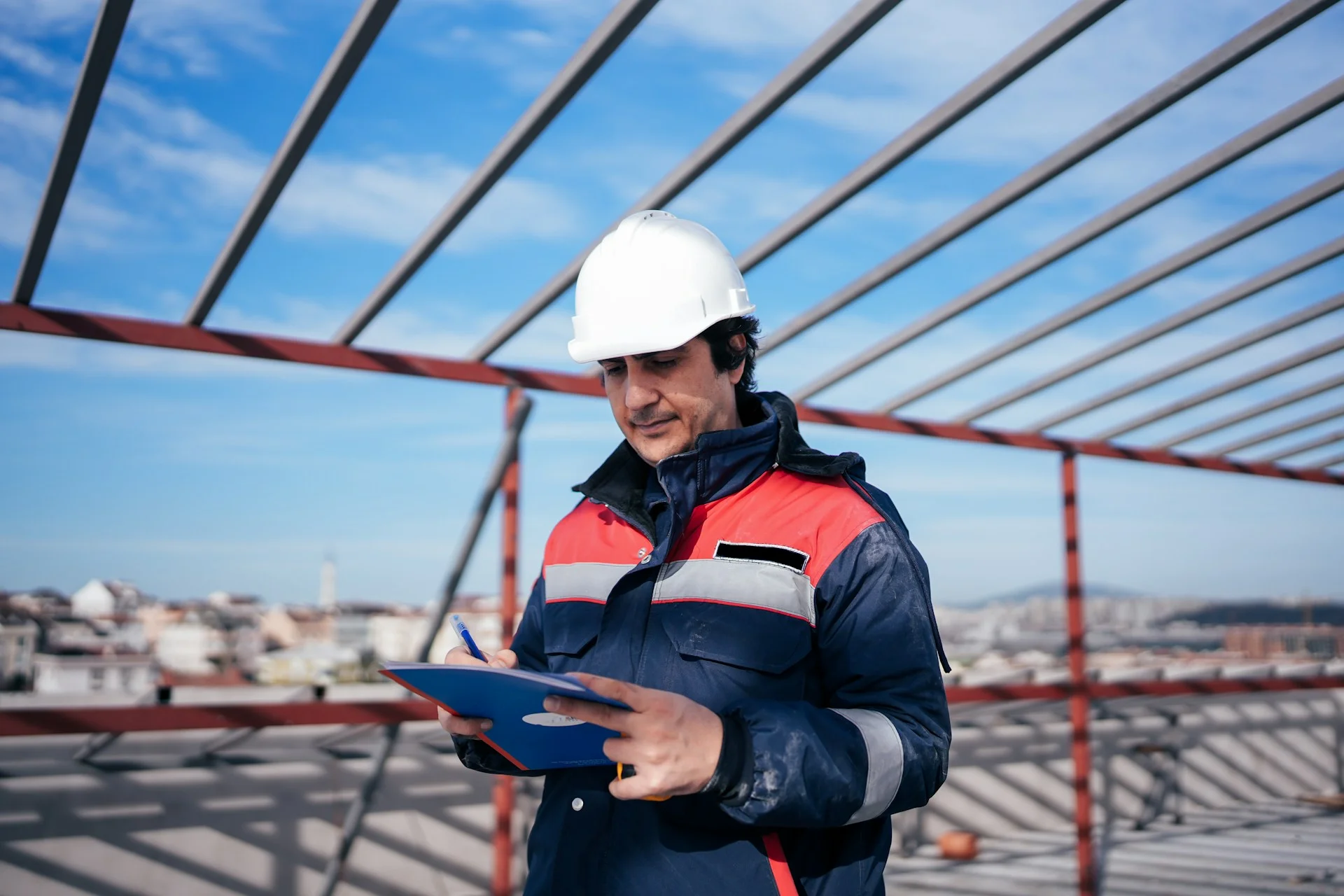 photo - a man looking at his notes on a construction site he is managing.